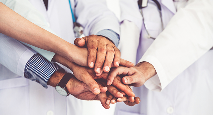Team of doctors and nurses with their hands in the middle of each other
